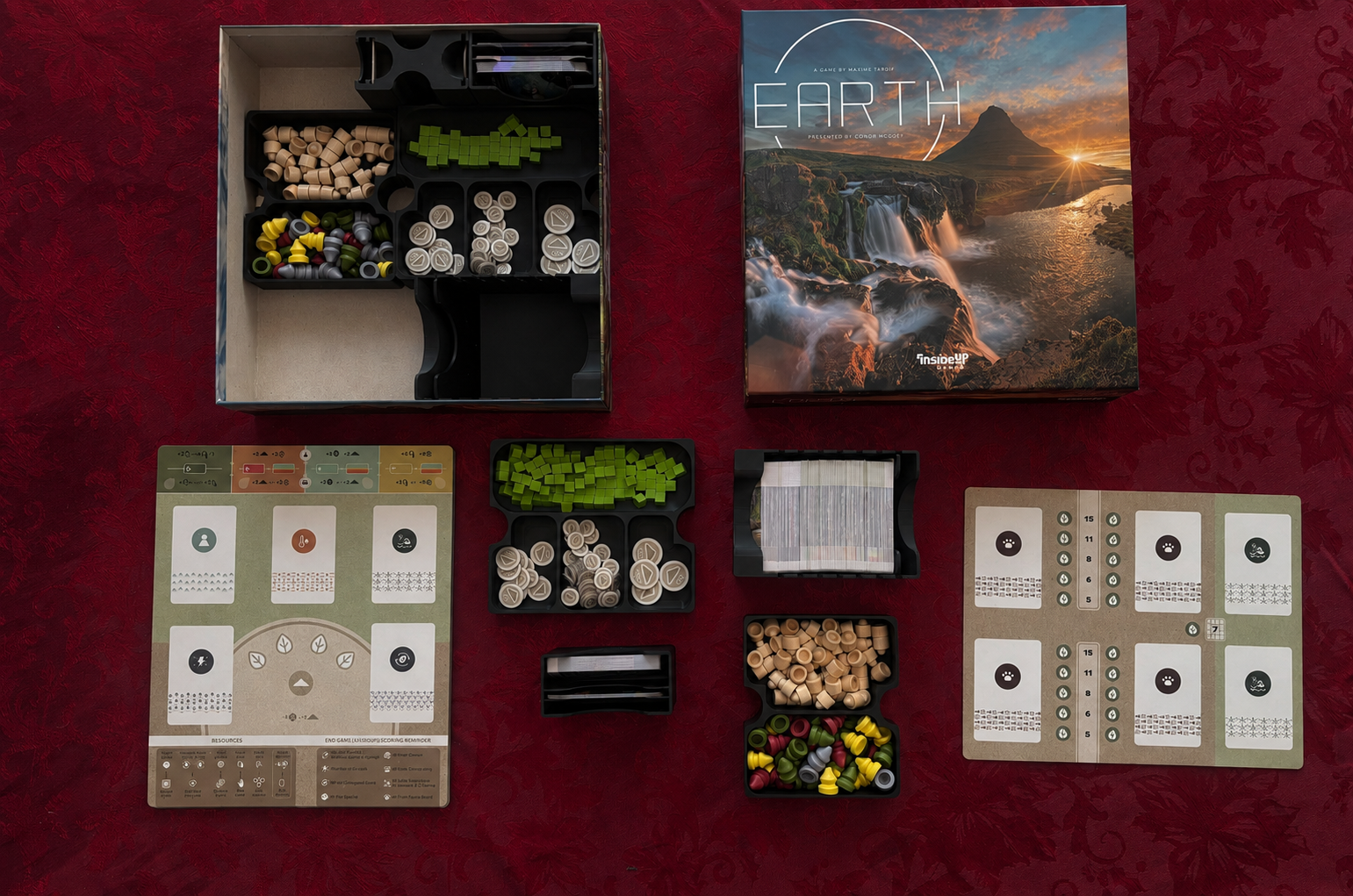 Overhead flat lay of Earth board game by Inside Up Games, showing box, components, tokens, and player boards