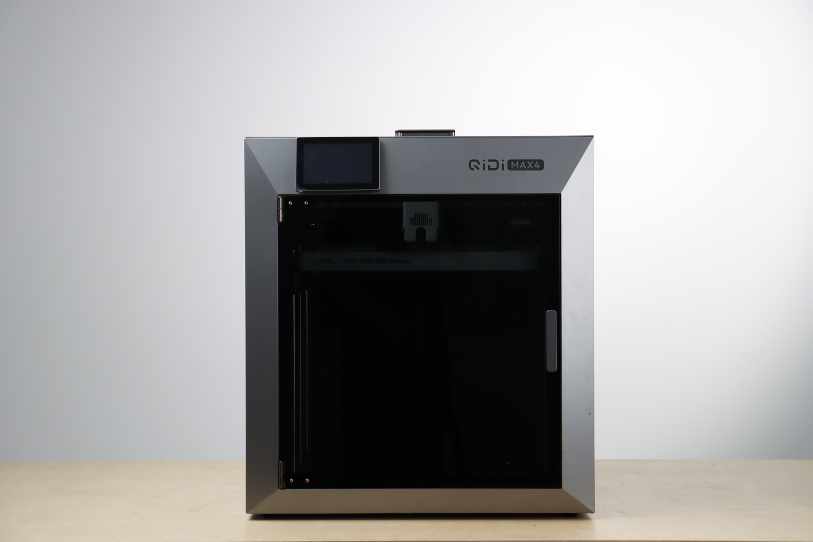 Front view of the QiDi MAX4 enclosed 3D printer with touchscreen and glass door on a wooden surface